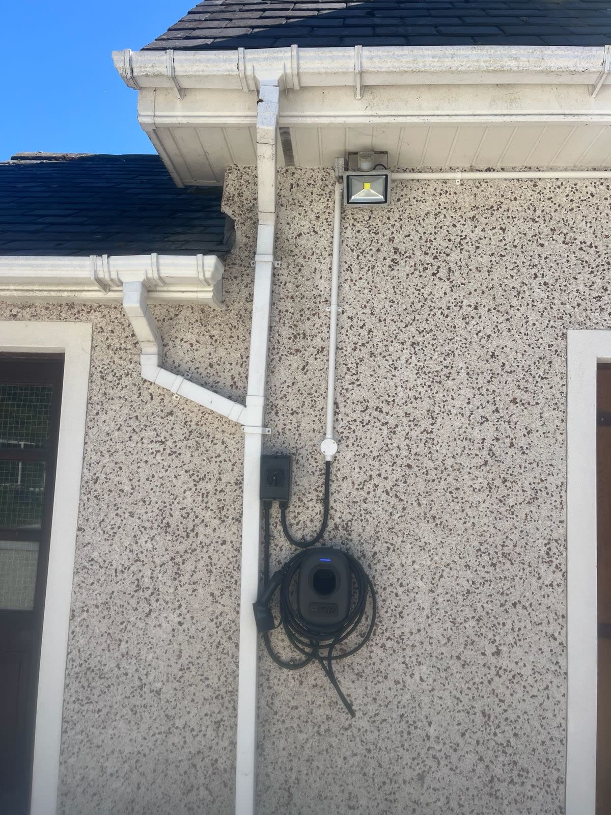 EV charger mounted below floodlight on dashed wall